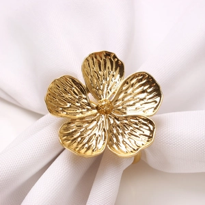 Elegant gold flower napkin ring with fine texture on white fabric for wedding decor