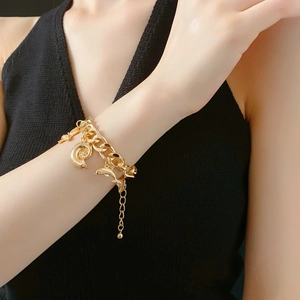 Detail of gold chain charm bracelet with sea dolphin starfish and shell pendants