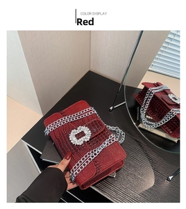 Detail of red crocodile pattern handbag with silver chain and rhinestone buckle