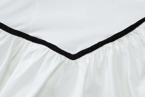 Gros plan d'une robe blanche avec bordure noire en V et détails plissés