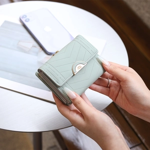 Close-up of a light green quilted faux leather tri-fold wallet with elegant gold metal clasp