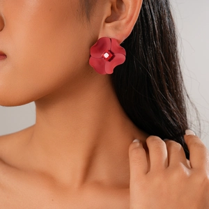 Detailed view of matte red flower earring with a central red crystal on model's ear