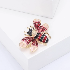 Detailed macro view of an enamel bee brooch with gold plating on a white geometric stand