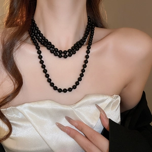 Detailed view of layered black pearl necklace on a model with elegant silk attire