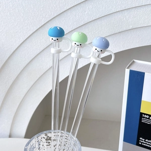 Detailed view of three glass straws with blue and green mushroom silicone covers