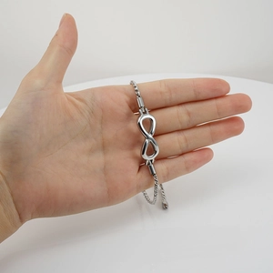 Polished silver infinity symbol bracelet with adjustable box chain held in hand