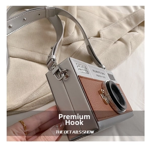 Detail of vintage camera-style crossbody bag with brown leather and silver metallic finish