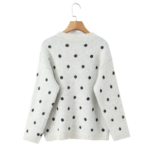 Dettaglio maglione grigio in maglia a pois neri su una gruccia in legno