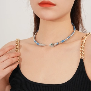 Detail of silver snake choker with blue accents and green gemstone eyes on neck