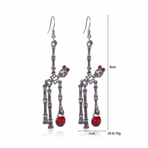 Detail of vintage silver skeleton earrings with red bow and pumpkin basket details