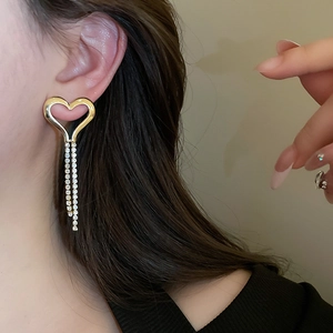 Close-up of heart-shaped rhinestone tassel earrings worn by a model in a luxury style