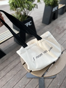Detailed view of canvas tote bag texture with black lettering on wooden table