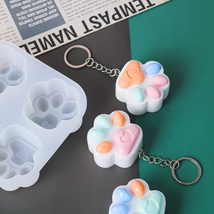 Detail of cat paw silicone mold with finished heart-shaped resin keychains in pastel colors