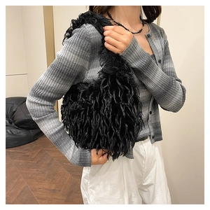 Detail of a black fluffy faux fur shoulder bag with stylish fringe texture on a model
