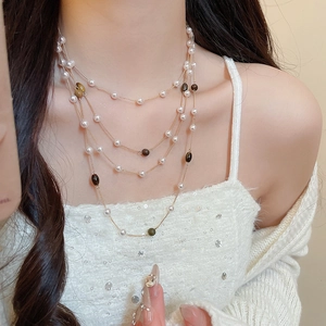 Dettaglio di una collana multistrato con perle occhio di tigre e perle su una modella