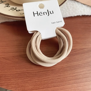Close-up of beige elastic hair scrunchies set on a branded display card and wooden surface
