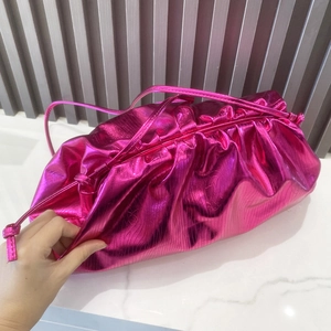 Detailed close-up of rose red metallic pleated cloud bag on marble surface