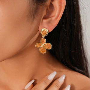 Detailed close-up of a gold-plated earring featuring a textured orange flower pendant