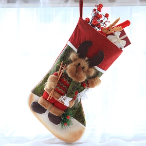Detail of Christmas stocking with plush reindeer motif, red berries and gift box decor