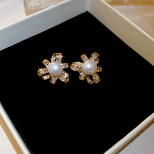Detailed macro shot of gold bow knot pearl earrings with zircon inlay on black velvet