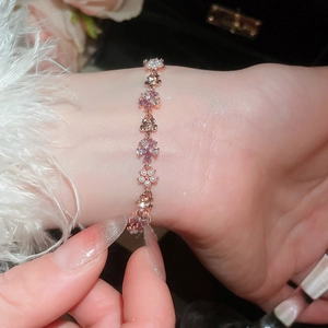 Macro view of rose gold flower bracelet with pearls and purple crystals on wrist