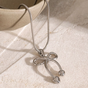 Macro shot of silver bow pendant with heart drops on sleek snake chain necklace