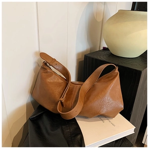 Close-up of brown textured leather shoulder bag with adjustable strap in a minimalist setting