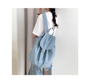 Vista laterale dello zaino in nylon azzurro con spalline regolabili e chiusura a patta