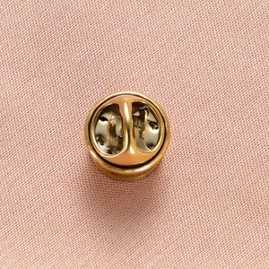Detailed back view of a golden round metal pin clasp showing internal spring structure