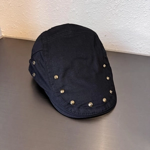 Dettaglio del berretto nero vintage con rivetti metallici e occhielli di ventilazione