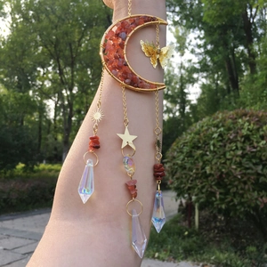 Macro detail of moon-shaped suncatcher with golden butterfly and orange crystals