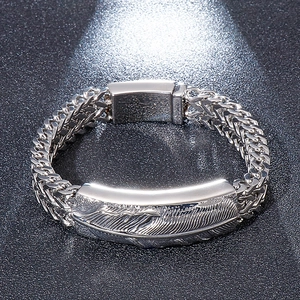 Close-up of hip hop style wheat chain bracelet featuring a detailed feather engraved plate