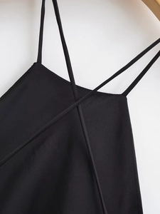 Detail view of black satin dress featuring thin cross shoulder straps and premium texture