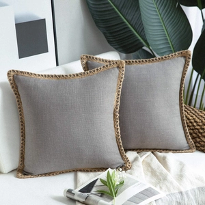 Detail of grey linen pillow covers with jute woven lace on a modern white sofa