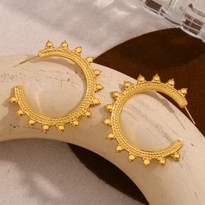 Macro shot of gold-plated hoop earrings featuring wheat pattern and studded details