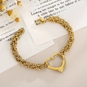 Close-up of golden heart pendant bracelet with intricate chain weave on vintage paper