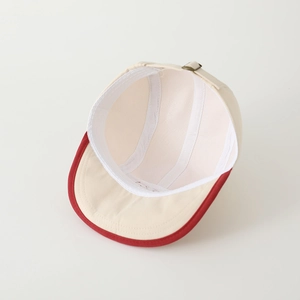 Detail view of baby baseball cap with red brim, breathable mesh lining and metal buckle