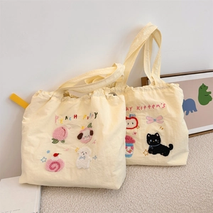 Detail of canvas tote bags featuring cute puppy embroidery and drawstring design