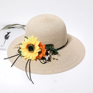 Detail of summer straw hat with yellow sunflowers, green leaves, and black ribbon detail