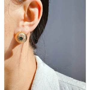 French vintage gold earrings with green gemstone and sunburst texture worn by model