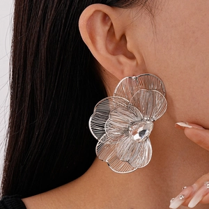 Close-up of oversized silver flower earrings with crystals on a female model