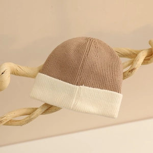 Gros plan sur la texture en tricot côtelé bicolore camel et crème du bonnet d'hiver bébé