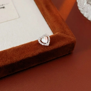 Detail of silver heart earring with zircon stones on a brown velvet jewelry display