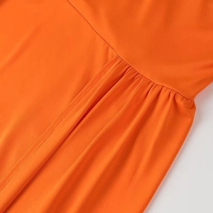 Détail de la taille de la robe orange avec plis élégants et coutures de précision