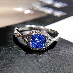 Détail d'une bague avec pierre bleue taille princesse et anneau entrelacé serti