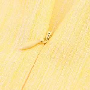 Macro view of textured yellow woven fabric featuring a matching invisible zipper