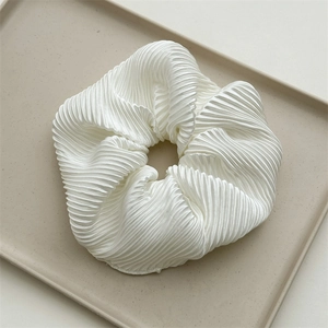 Detailed view of large white pleated hair scrunchie with silky luster and soft texture