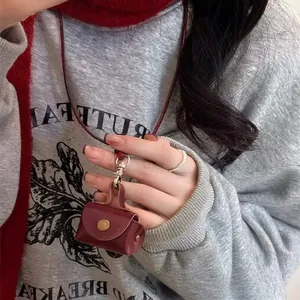 Dettaglio di una collana mini pochette in pelle bordeaux con bottone a pressione