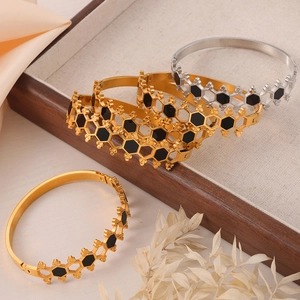 Gold and silver hollow hexagonal bangles with black acrylic inlay on a wooden tray