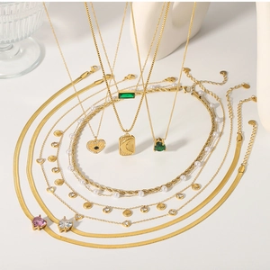 Detail of layered gold necklaces with heart zircons, shell charms, and pearl accents